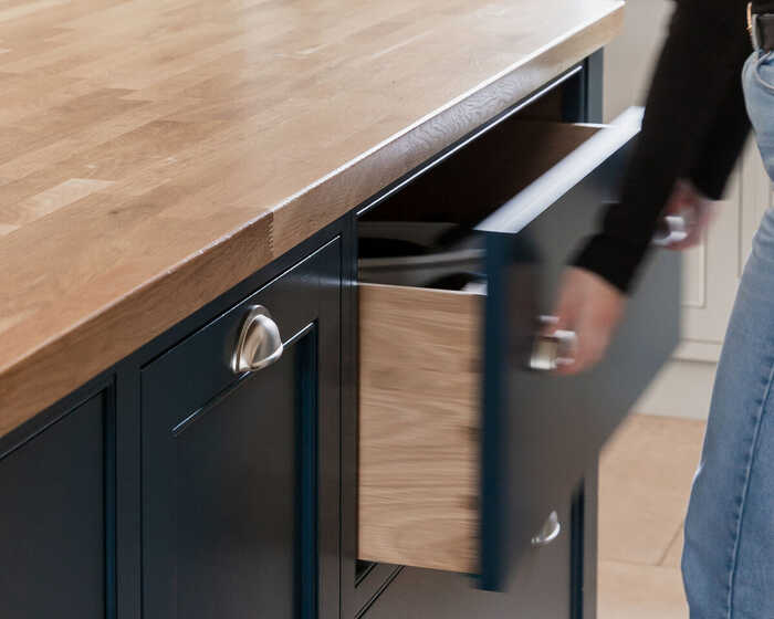 lady opening a bespoke kitchen cabinet draw integrated into a kitchen island with a wooden countertop